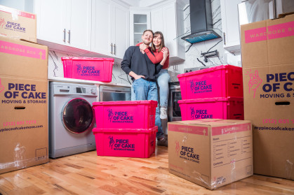 Couple surrounded by packing boxes and crates from Piece of Cake Movers